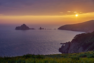 Rocky islands and peninsulas in the ocean at sunset.