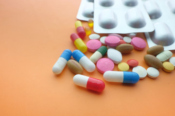  colorful pills and blister pack on orange background 