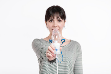 smiling brunette woman holding inhalation mask in front of her face. pulmonary diseases recovery...