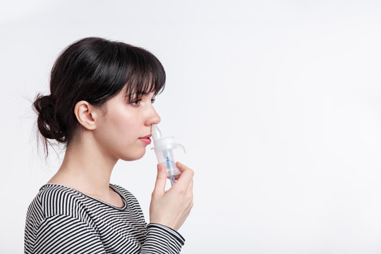 profile picture of brunette woman using nasal inhaler. patient inhale medicine