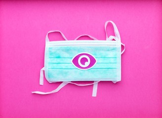 Masque chirurgical protection virus Covid sur arrière-plan rose avec symbole concept énergie caméra oeil éclair