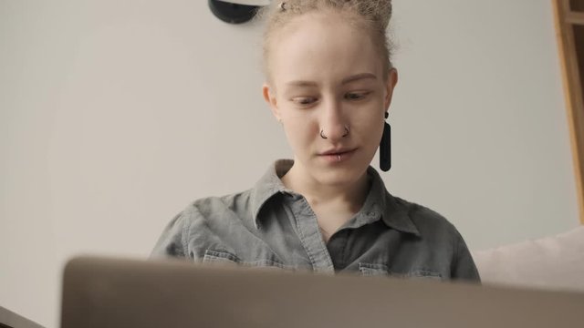 Concentrated amazing girl with dreadlocks indoors using laptop computer