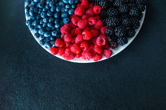 Mix of summer berries vitamins. Mulberry, raspberry and blueberry. Stylish layout on a black table.