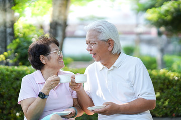  Senior couples happily sit and drink coffee in the morning at the park.