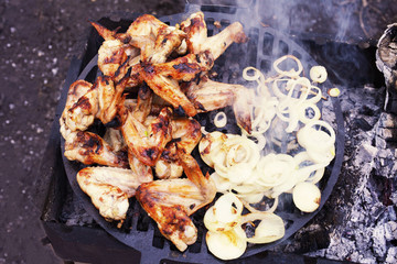 the process of preparing marinated chicken wings on the grill, chopped onion rings, top view