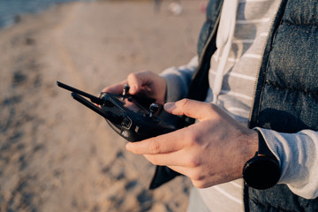 Drone remote controller in guy's hands on the breach on sunset