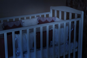 Baby bed crib with white and burgundy color pillows with laces