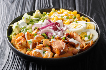 Chicken vegetable salad with avocado, corn, onion, eggs seasoned with yogurt close-up in a plate. horizontal