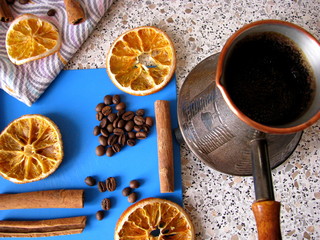 Turk with coffee, coffee beans, cinnamon, dried oranges on a stand and a towel.