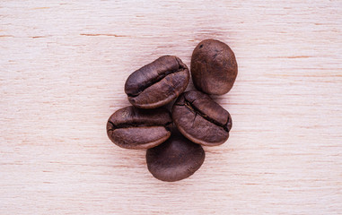 Five roasted coffee beans on a flat wooden surface flat lay top-down composition