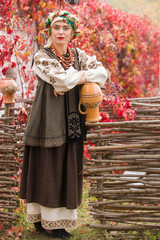 Beautiful girl in national dress. With an ancient clay pot. Antique clothing of the late 19th century. Beautiful dress and skirt on a woman. Beautiful autumn and leaves. Clothing of the late 19th