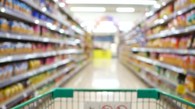 blur defocus of footage walking with cart in supermarket to buy food, drinks , household goods