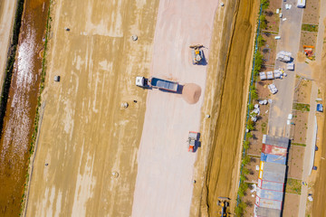 Aerial photo of bulldozer pours sand into the truck. On the construction site top view. Shooting from the drone.