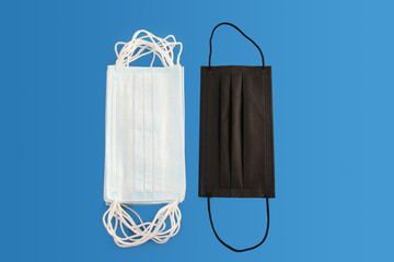 many white and one black protective antiviral medical masks, concept of the SARS-CoV-2 virus...