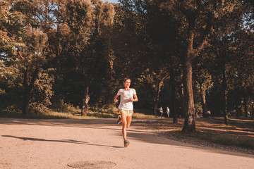 Giovane ragazza corre e si allena in solitudine in mezzo al verde del parco cittadino con...