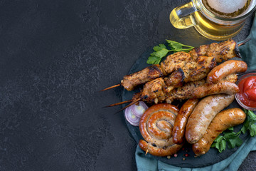 grilled kebabs and sausages with a glass of beer and tomatoes
