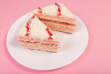 two pieces of cake on a white plate, on a pink background