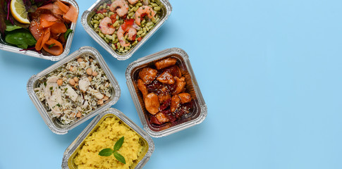 Food delivery. Different aluminium containers with healthy diet natural food. Top view on blue...