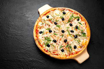 Pizza VENICE on a black background, tomato-based with mozzarella, grilled chicken, olives,green and onion.