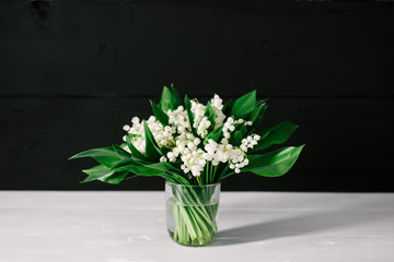 bouquet of lilies of the valley on a white and black wooden background