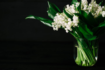 bouquet of lilies of the valley on a black wooden background