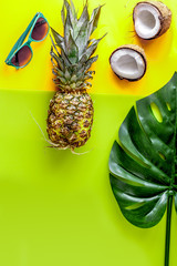 summer mix with sun glasses, pineapple and coconut yellow background top view mockup
