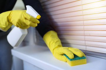 hands in gloves wiping home surfaces with antibacterial spray. cleaning concept 