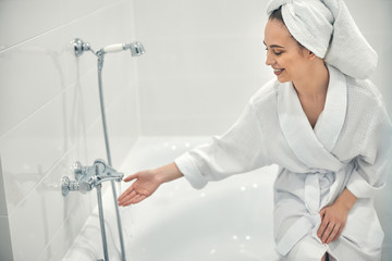 Cheerful lady with white towel on head going to take bath