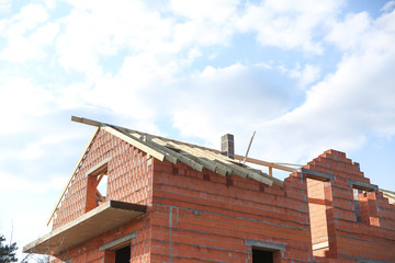 construction of a country brick house. top floor of a country house against the sky. unfinished house without a roof.