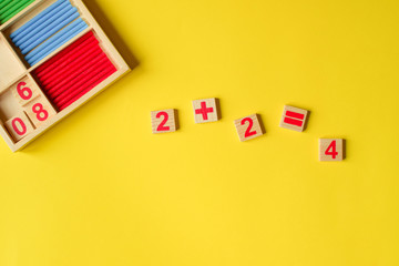 Wood numbers on a yellow background. Primary school, first grade. Mathematics. Two plus two equals...