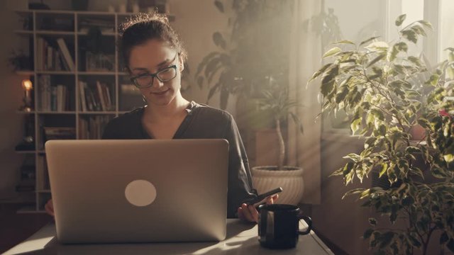 The girl in glasses has an online interview, she looking in laptop, talks about her advantages. Medium cinematic shot. 
