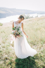 Bride in a luxurious white wedding dress in nature at sunset	