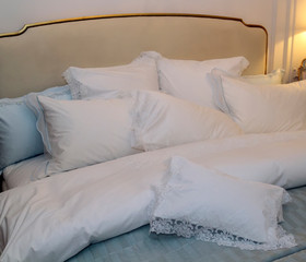 Close-up of new blanket with decorative white pillows in bedroom in sample model of hotel or apartment