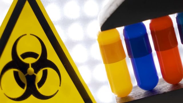 A yellow biohazard sign on the side of the medicine pills