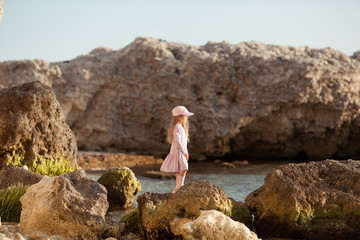 Happy pretty girl walks along the sea coast against the background of the sea, from behind a beautiful landscape