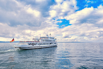 Naklejka premium Ferry sails through calm waters under cloudy skies