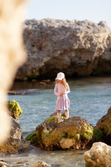 Happy pretty girl walks along the sea coast against the background of the sea, from behind a beautiful landscape