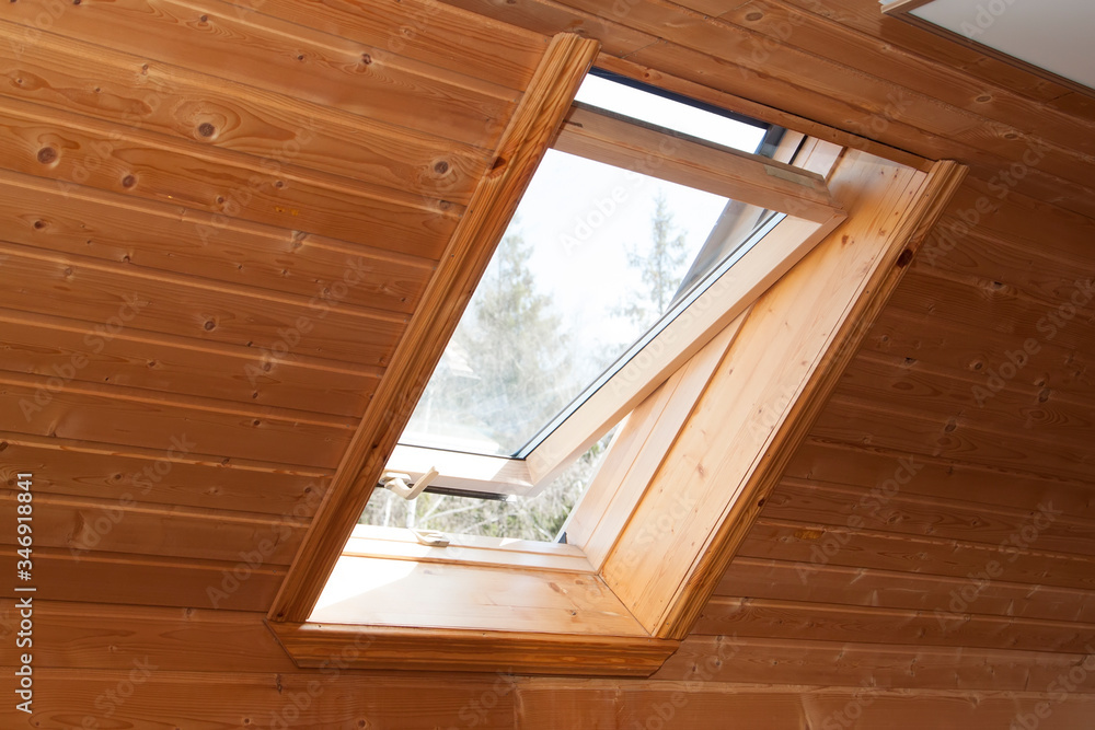 Poster open dormer window in wooden house in the attic. room has sloping ceiling made of natural eco-materi