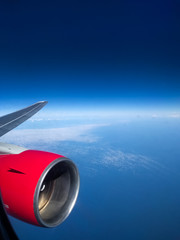 Fototapeta premium View from the airplane porthole of the turbine and the endless blue of the sky with rare clouds