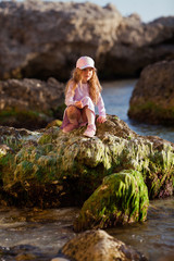 Happy pretty girl walks along the sea coast against the background of the sea, from behind a beautiful landscape