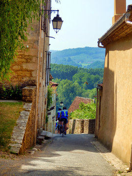 Fototapeta French cycling club descending the steep streets of Limeuil in Dordogne, France