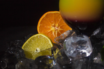 Colorful juice cocktail with straw on the black background. Citrus fruits and ice. Multi color cocktail. Fresh and healthy  ..smoothie. Concept of raw food fruits and vegetables. Close up