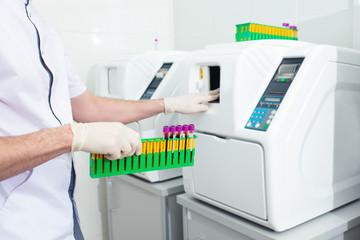 Hands of a laboratory assistant in gloves close up conducting research with the help of an analyzer