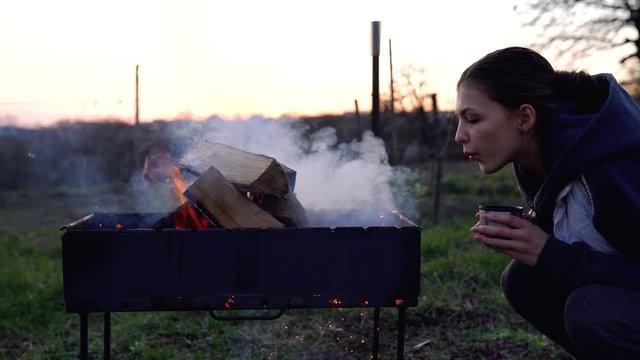 Attractive brunette girl with cup in her hands blowing fire