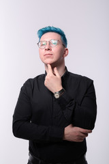 Fototapeta premium Young stylish blue haired man flirty and lusty stares in a camera, studio portrait on light background