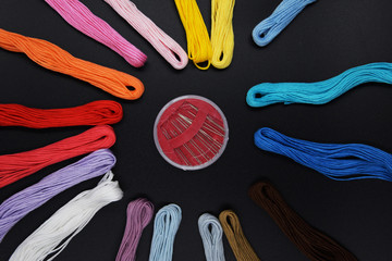 Different colors of embroidery threads are placed in a circle, and several needles lie in the middle. The concept of quarantined classes at home is a favorite hobby.