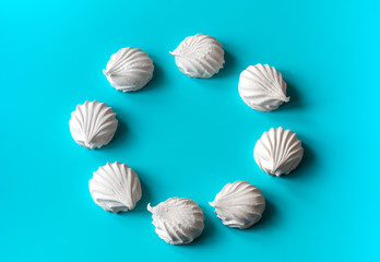 white vanilla marshmallows laid out in a circle on a blue background. magic circle made of white marshmallows. place for text. free space