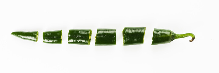 Cut pieces of hot green pepper in a row insulated on a white background