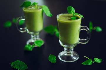 Fresh avocado smoothie poured into a glass with mint leaves on a black table. Concept of a healthy diet and healthy lifestyle. Vegan food. Detox drink