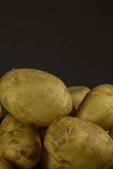 Raw fresh organic potatoes on wooden table against dark background.